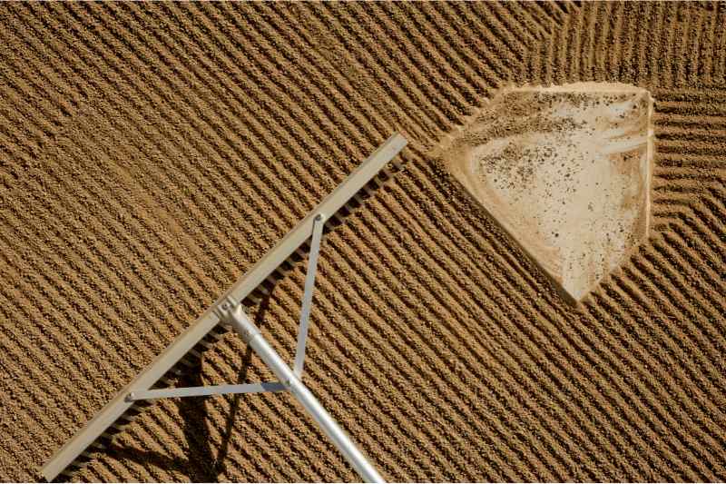 rake grooms dirt of infield diamond