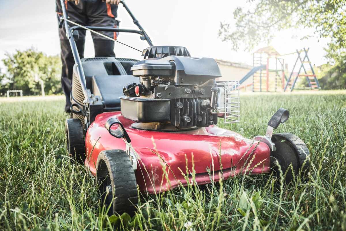 pushing a red lawn mower