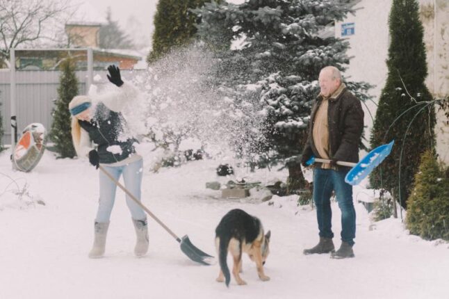 An elderly couple shoveling snow