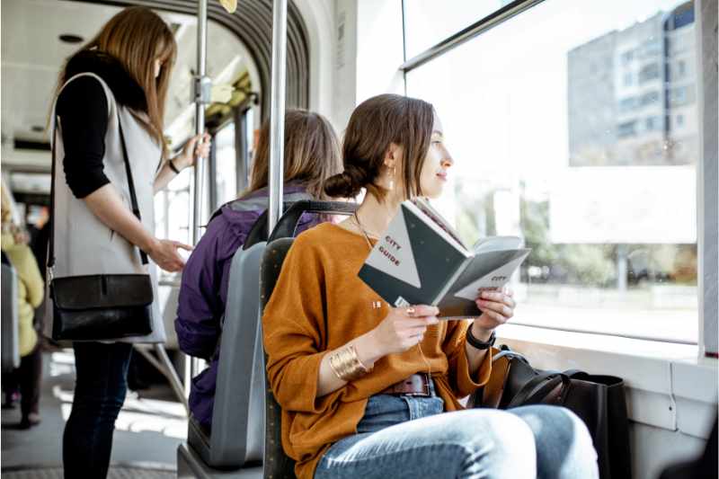 female sitting on a bus and reading a book