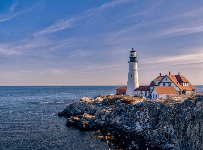 A view of Portland Head Light, a historic lighthouse in Cape Elizabeth, Maine, on the right and water on the left