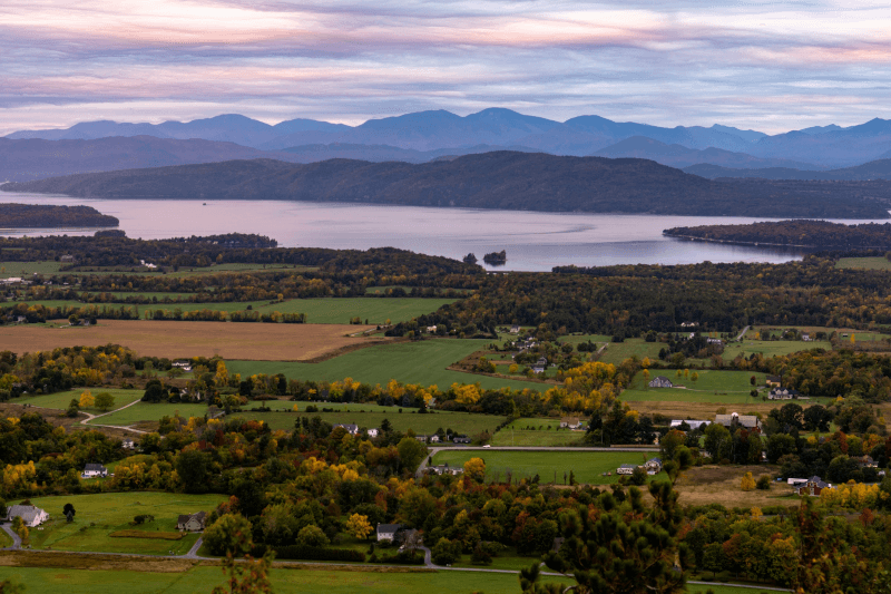 An aerial view of Champlain Valley in Vermont at sunrise, with water and hills in the background