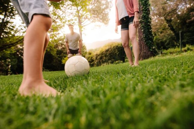 Family playing football in garden lawn