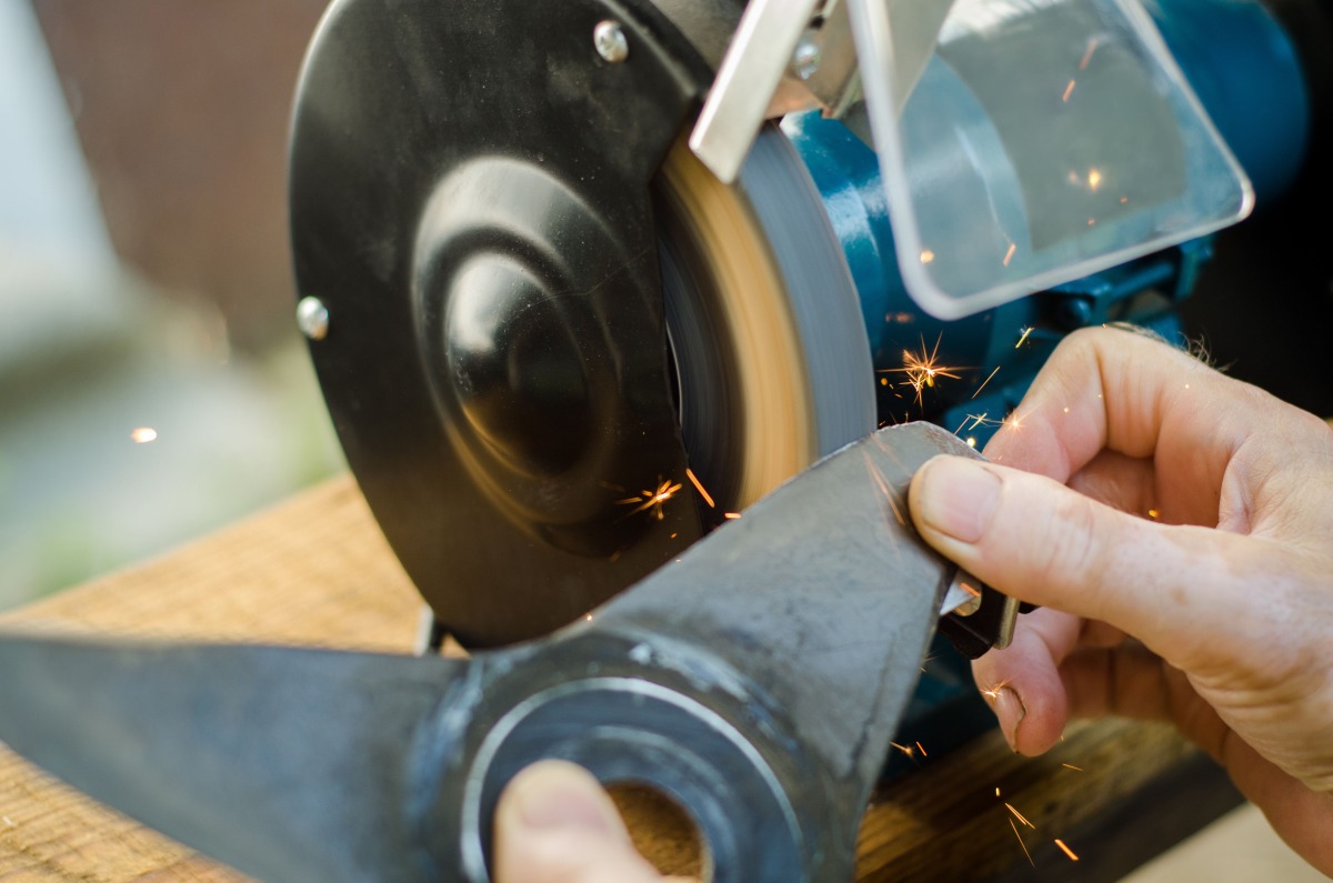 Worker sharpening his lawn mower blade