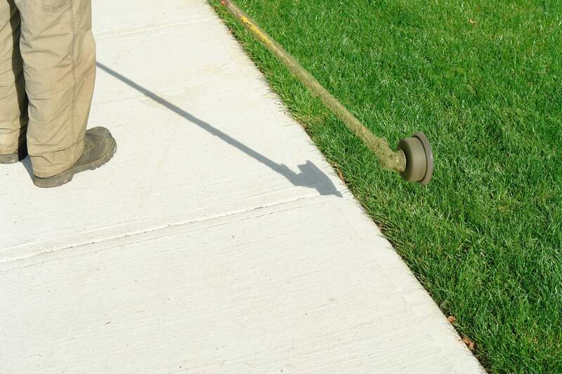 person edging lawn along sidewalk