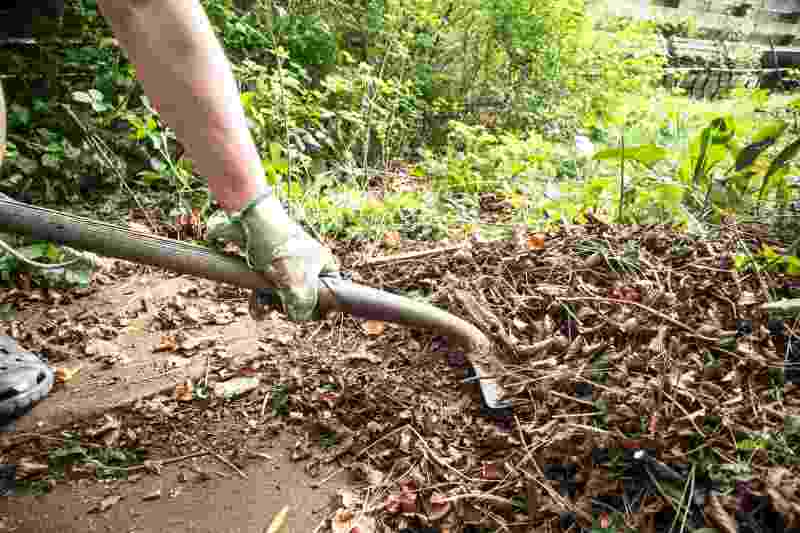 Man shoveling garden waste leaves