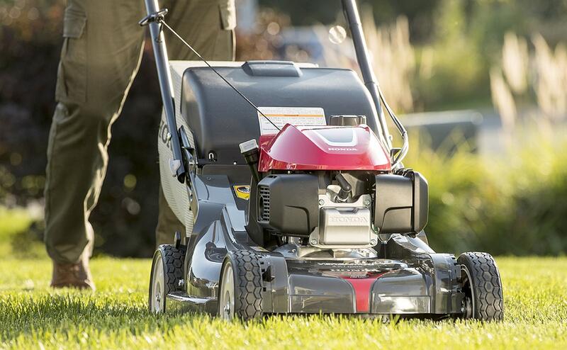 man pushing a self-propelled lawn mower