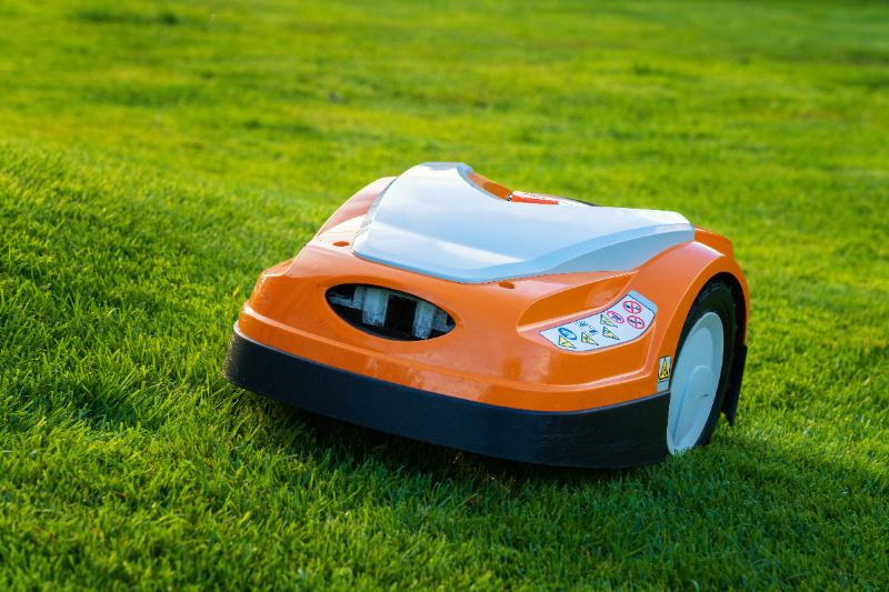 Automatic lawn robot mower moves on the grass slope in the lawn.