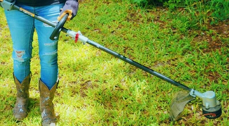 person using a string trimmer in lawn