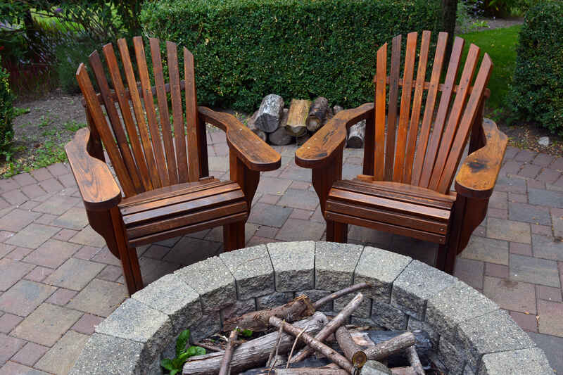 wood campfire chairs on a paver patio in front of a stone fire pit