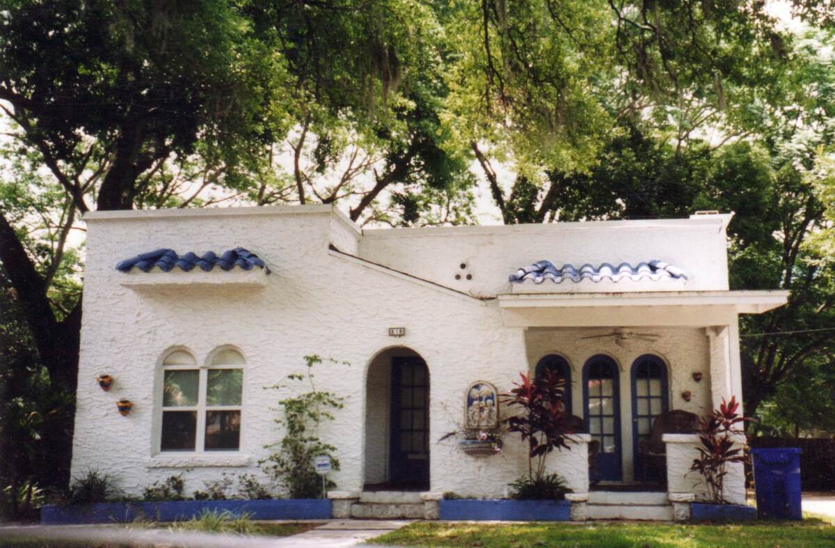 A house in Orlando, Florida with a lawn and some landscaping plants around it