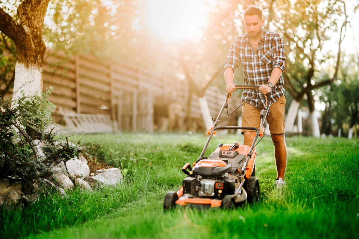 man cutting the grass in backyard garden using lawn mower