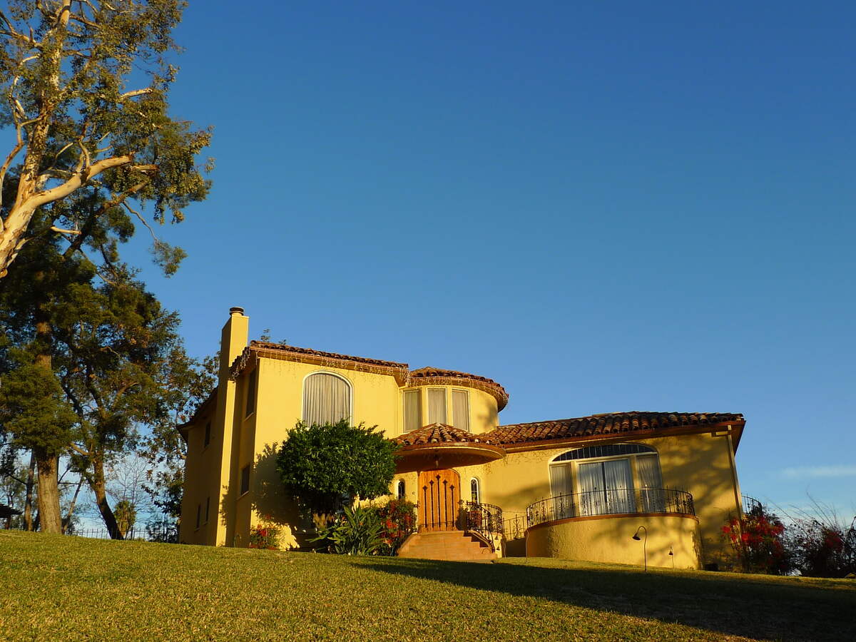 A lawn in front of a house with holiday lights during the day