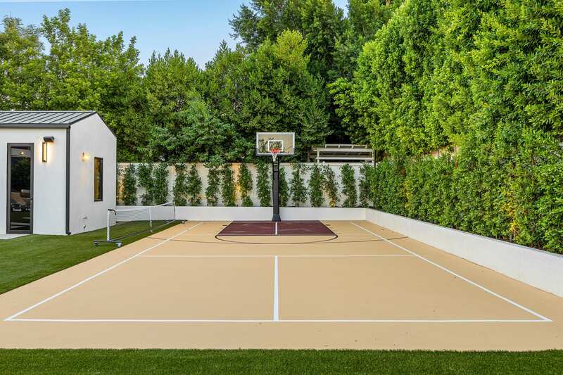 Modern backyard sports court with greenery. 