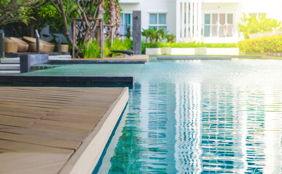 Outdoor swimming pool with blue water near the garden.