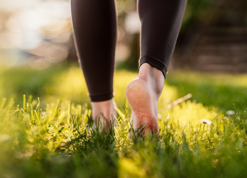 Woman walking barefoot on fresh green grass