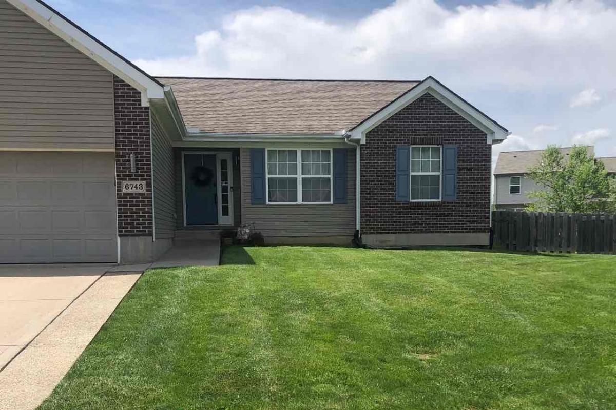 lawn in front of a house with cloudy sky in background