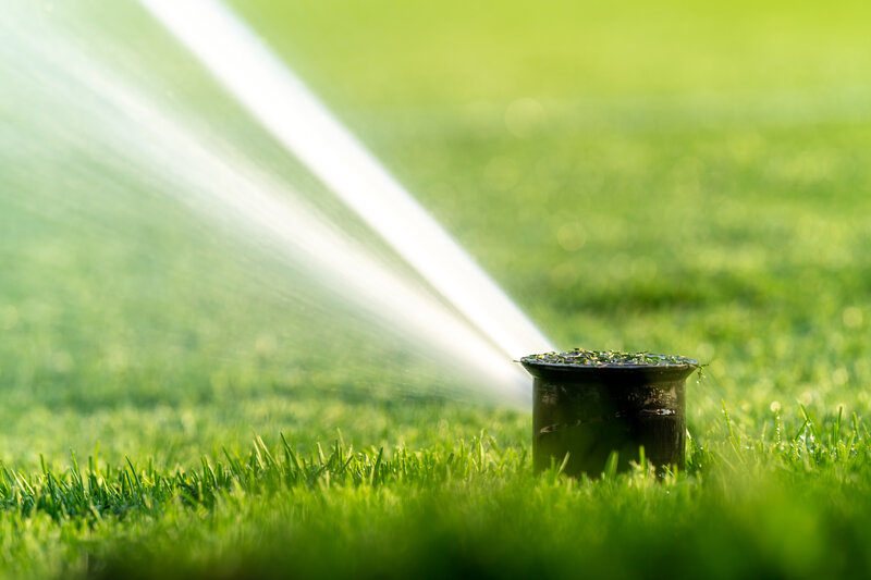 a sprinkler watering the lawn so it becomes moist