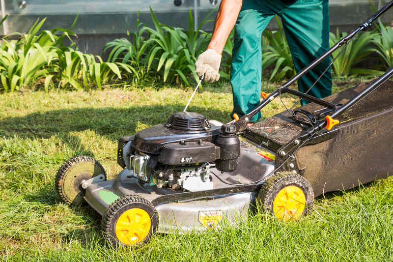 person starting a lawn mower in a lawn