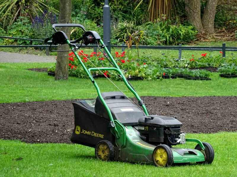 A green lawn mower in a grassy lawn