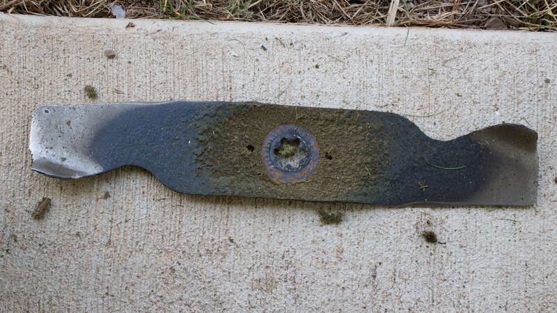 a lawn mower blade placed on a concrete surface