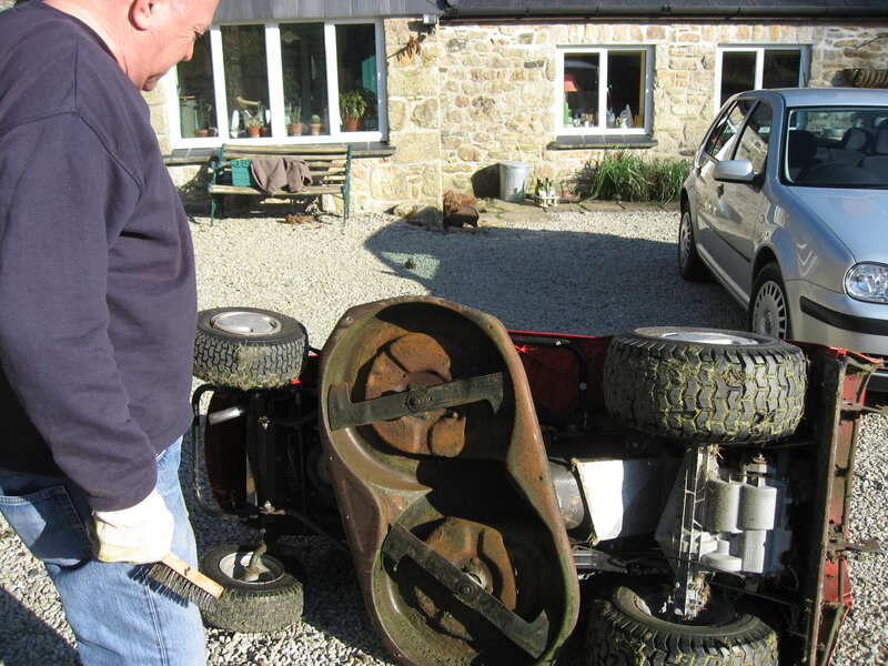person cleaning a mower deck