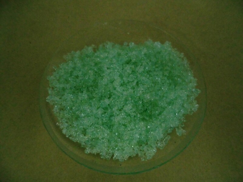 green colored crystals of iron sulfate in a bowl