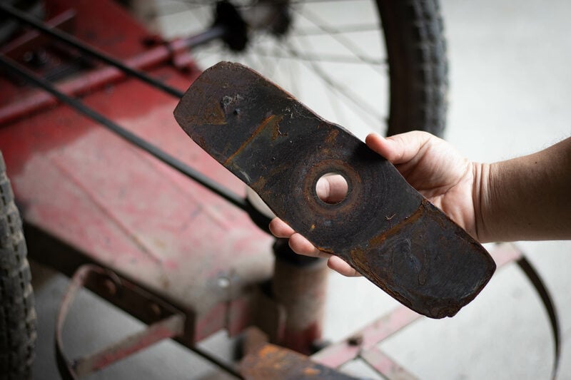 Man holding a dull and rusted lawn mower blade