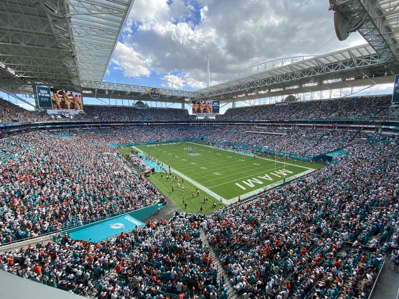 Full crowd at Hard Rock Stadium during an NFL game under a bright sky.