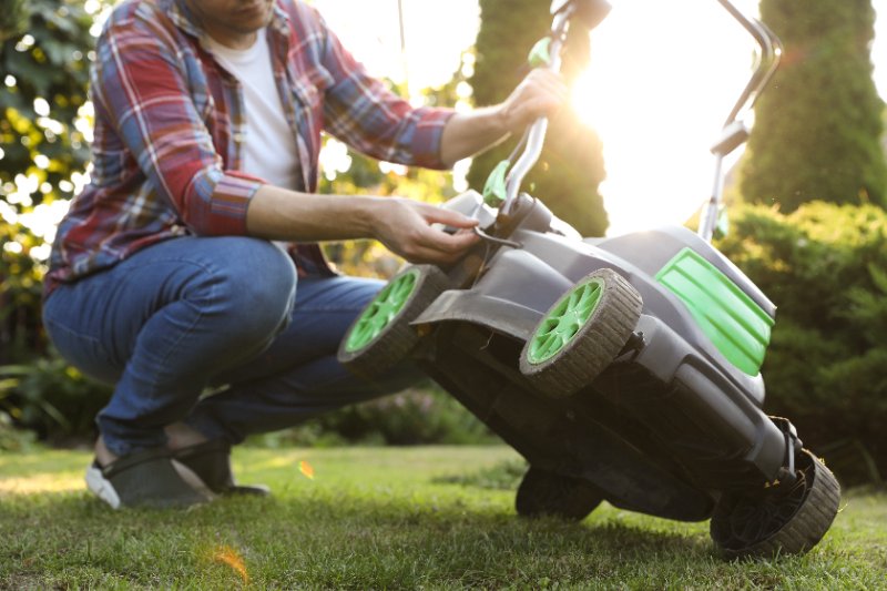 closeup of a man fixing lawn mower in garden