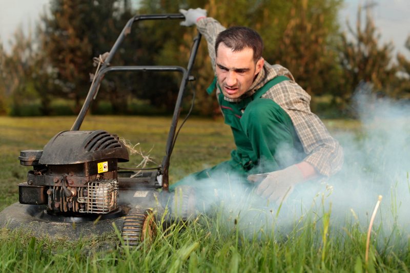 closeup of smoke coming out of a mower with a man nearby