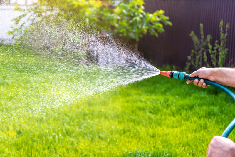 a person watering his clay soil type grass