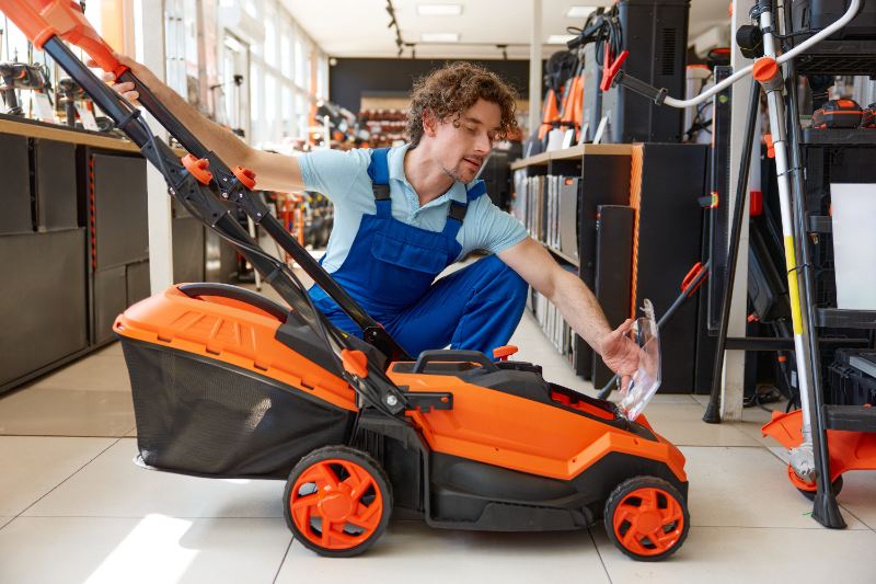 A male customer looks over an electric lawnmower at a garden supply store.