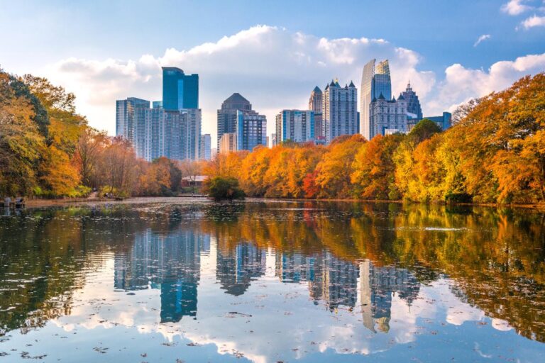 View of Atlanta with reflection of the skyline in water and colorful, fall leaves in between.