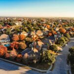Picture from a drone in residential area of the Dallas, Texas suburbs with colorful fall foliage leaves under a blue sky.
