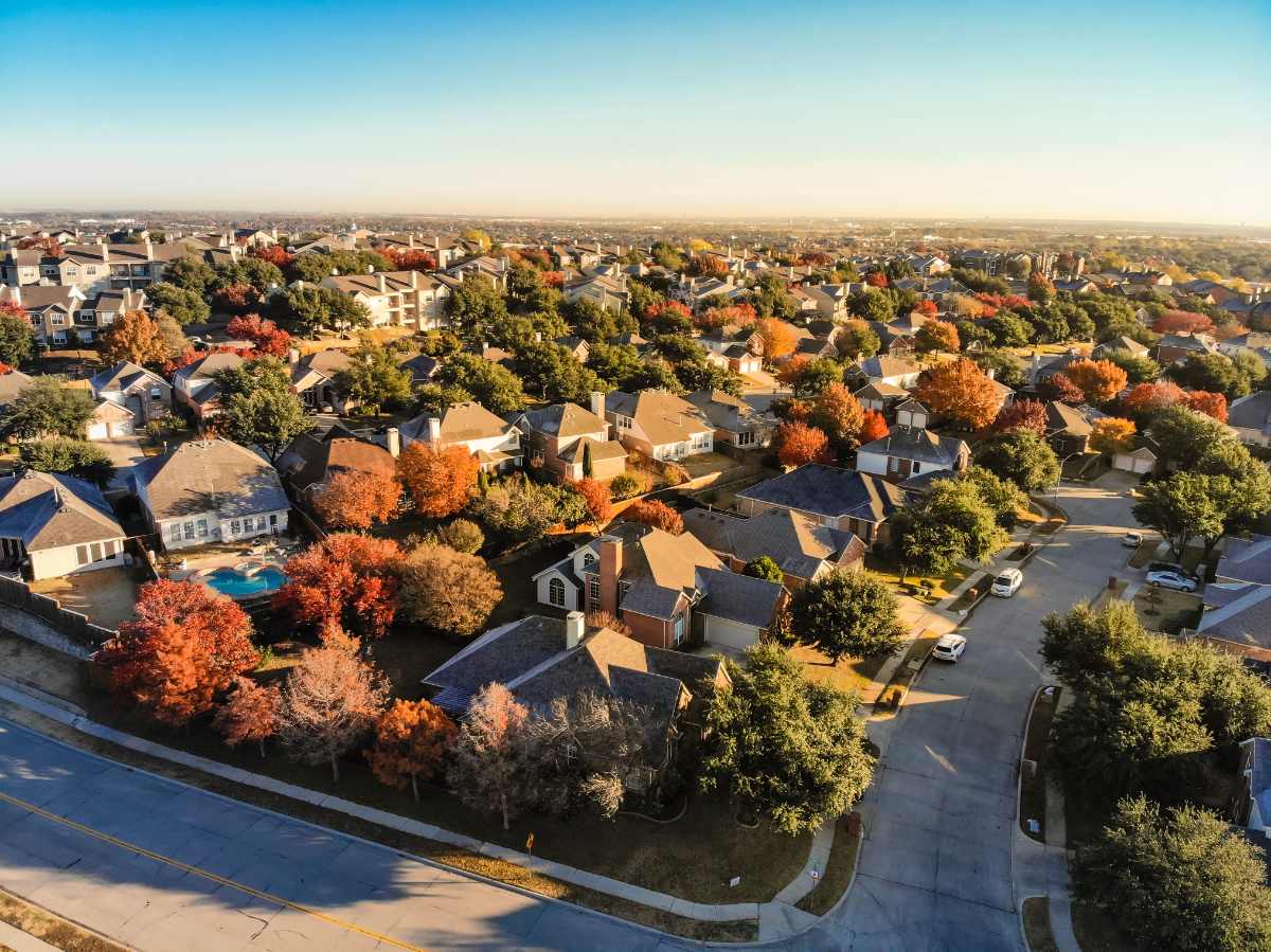 Picture from a drone in residential area of the Dallas, Texas suburbs with colorful fall foliage leaves under a blue sky.