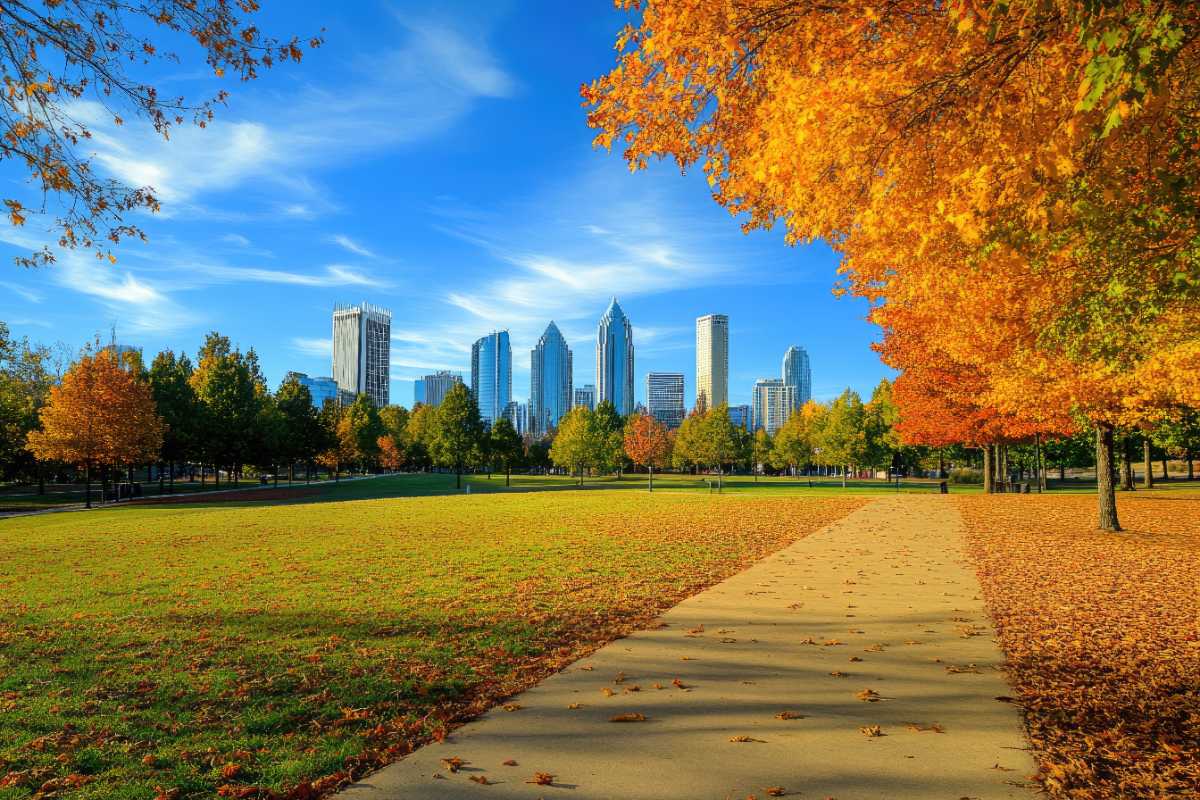 The skyline of downtown Charlotte, N.C., is seen behind a park during fall with trees and leaves changing colors.