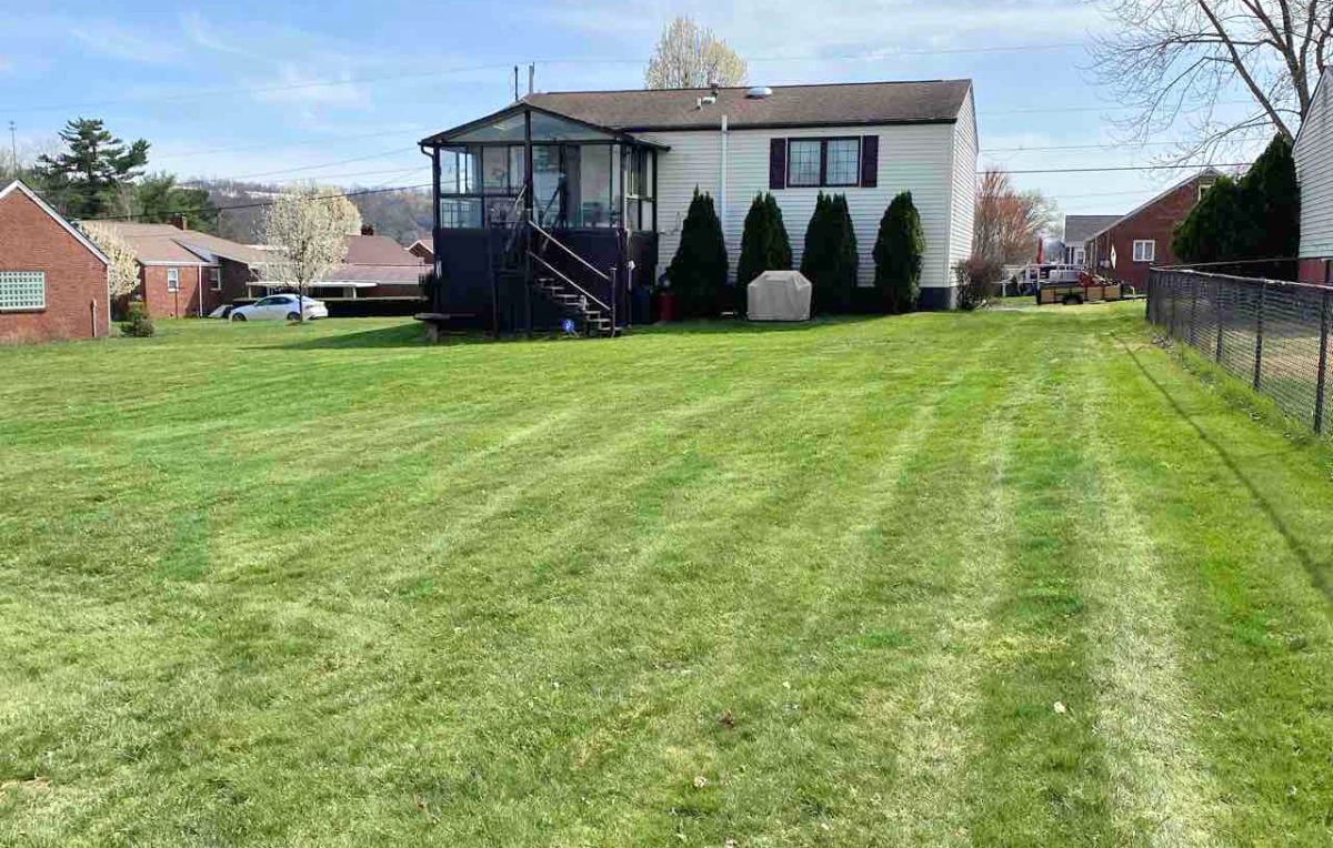 A well-maintained suburban neighborhood with trees, manicured lawns, and houses on a sunny day.