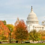 Fall foliage including colorful trees and leaves surround the Capitol building in Washington, DC.