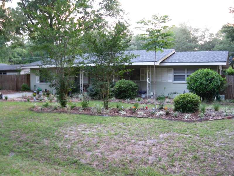 landscaped backyard with mulched bed of trees and plants