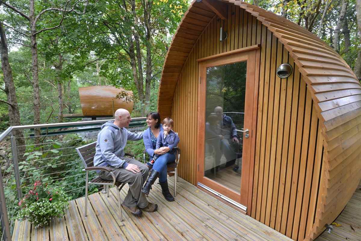 Family sitting on the porch of their glamping rental set in the woods