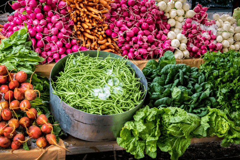 A farmers market stand in Vermont with radishes, beans, and other colorful produce