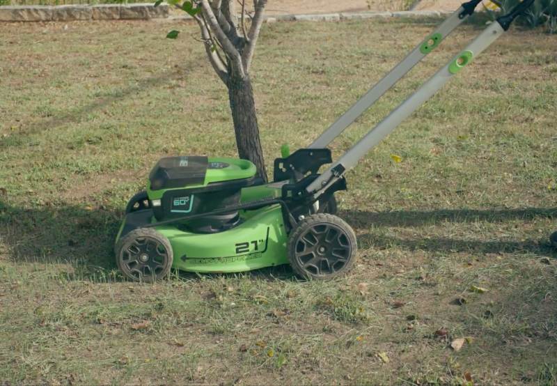 LawnStarter pro Carlos pushes a lawn mower across a residential yard during a first-time mowing service.
