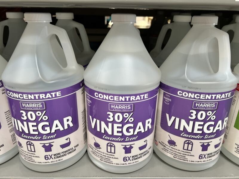 Three gallon jugs of Harris 30% Vinegar Concentrate with lavender scent displayed on a store shelf.