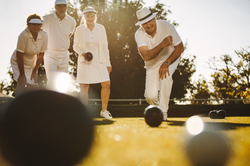 Senior people playing lawn bowls in a park